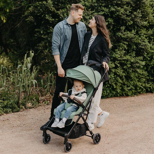 Familie mit Kind im Reisebuggy beim Spaziergang im Park.