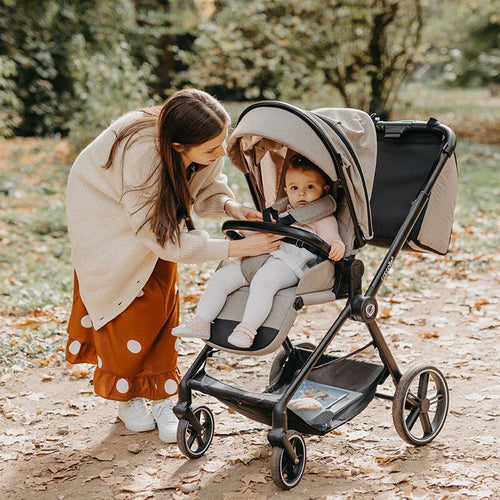 Mutter beugt sich liebevoll über den Kinderwagen, um mit ihrem Baby zu interagieren.