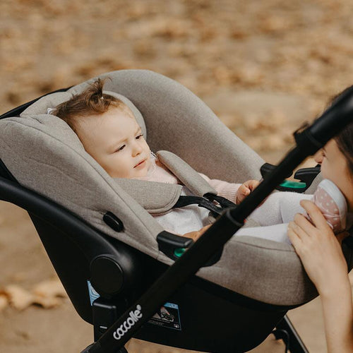 Nahaufnahme eines nachdenklichen Babys, das sicher im Kinderwagen sitzt.