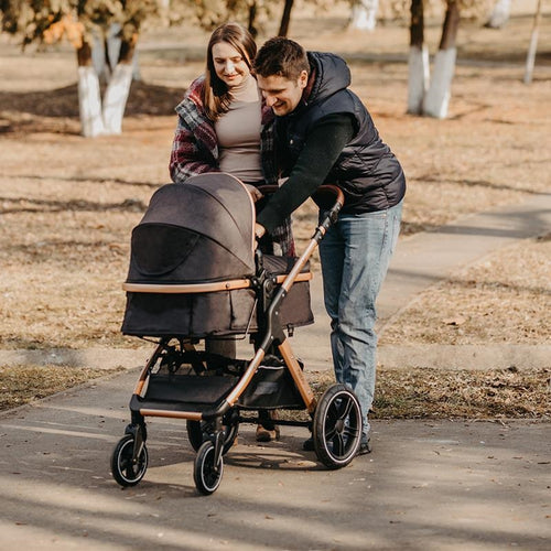 Ein Paar schaut liebevoll auf ihren Kinderwagen mit einem schlafenden Baby im Herbstpark.